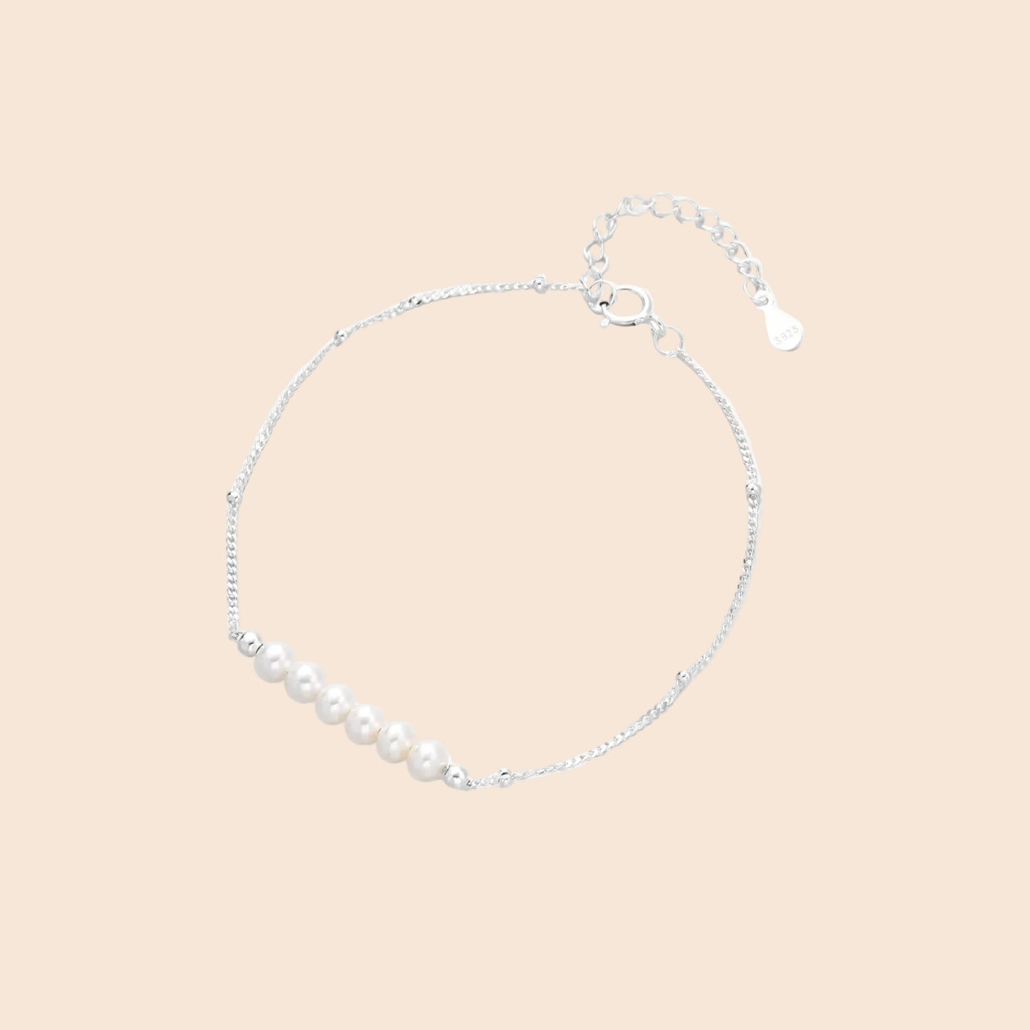 Delicate rhodium-plated silver chain bracelet with row of small baroque pearls centered on white background.