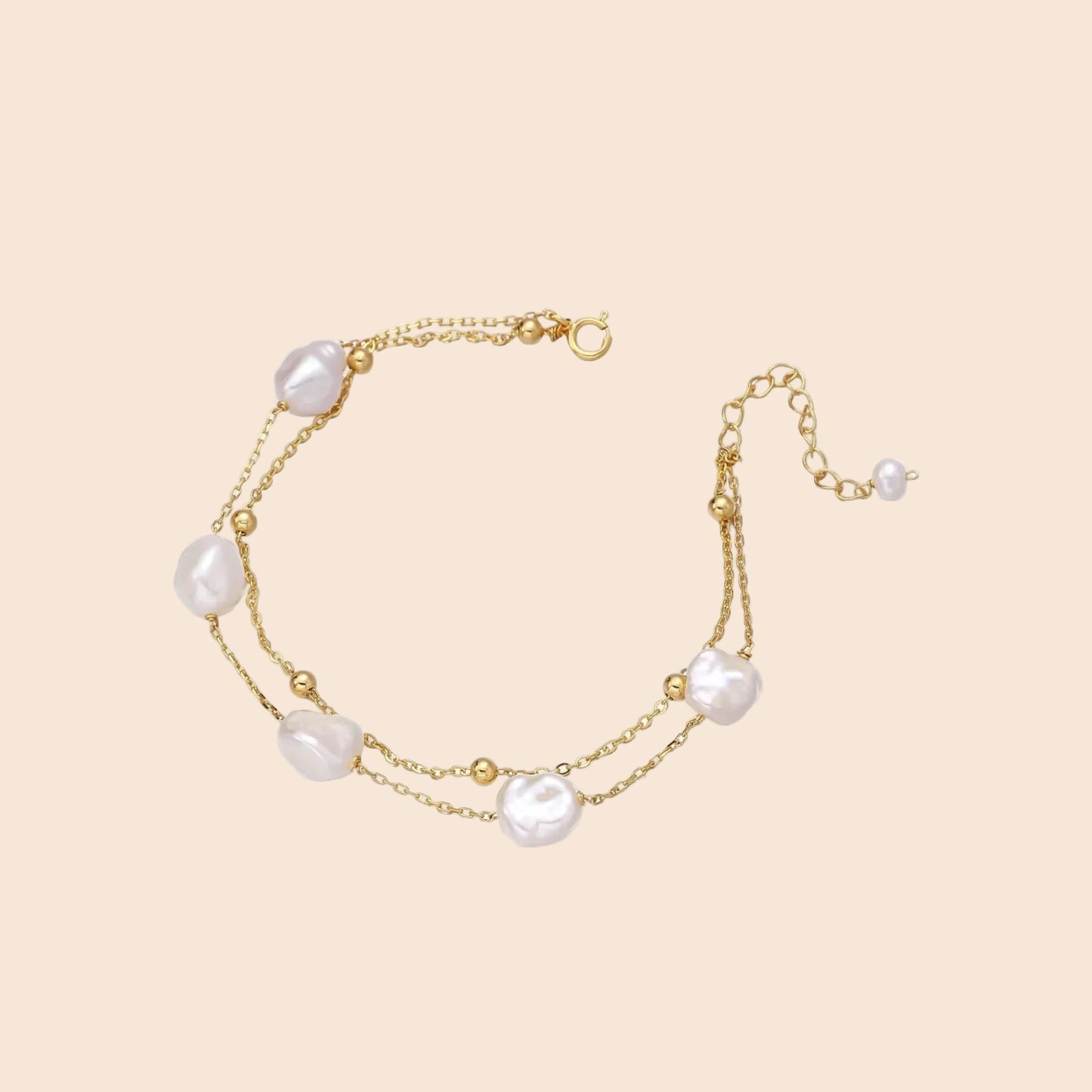 Double-strand gold bracelet with irregular baroque pearls and smooth freshwater pearls on cream background.