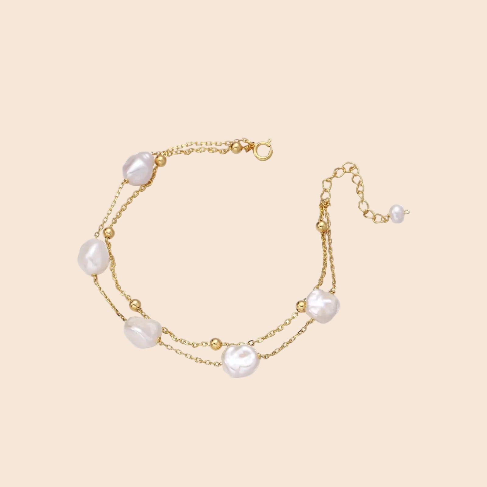 Double-strand gold bracelet with irregular baroque pearls and smooth freshwater pearls on cream background.