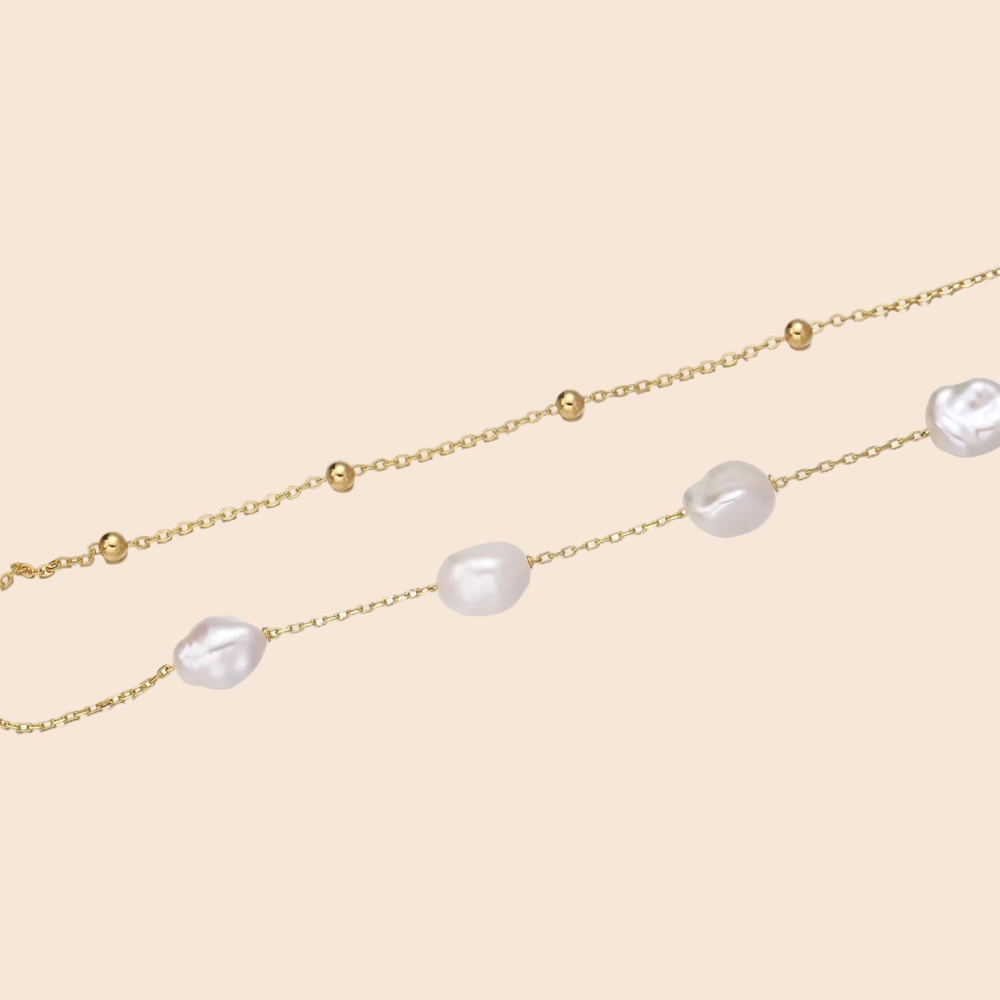 Double-strand gold bracelet with irregular baroque pearls and smooth freshwater pearls on cream background.