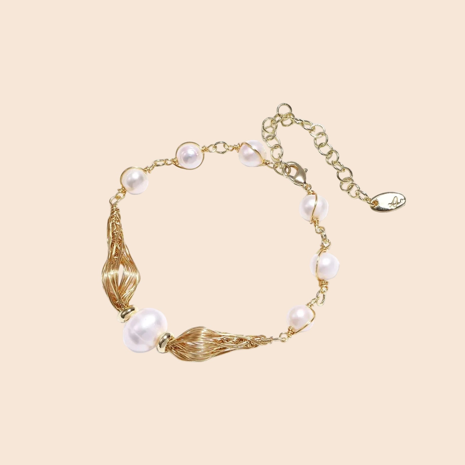 Adjustable gold bracelet with freshwater pearls and textured filigree beads on white background, showing clasp detail.