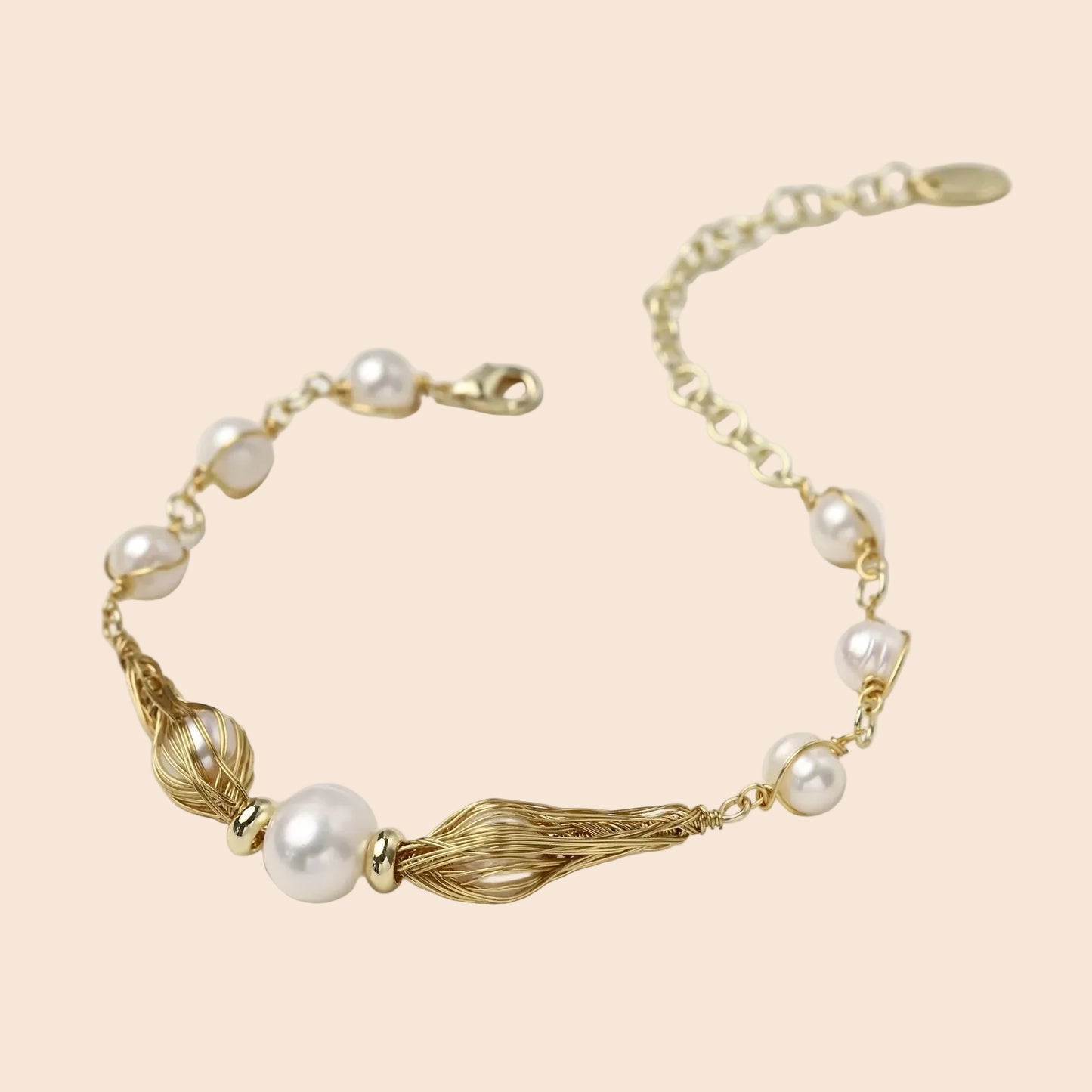 Adjustable gold bracelet with freshwater pearls and textured filigree beads on white background, showing clasp detail.