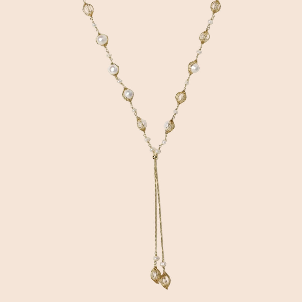 Adjustable gold lariat necklace with freshwater pearls nested in delicate cage settings and Y-shaped tassel drop