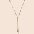 Adjustable gold lariat necklace with freshwater pearls nested in delicate cage settings and Y-shaped tassel drop