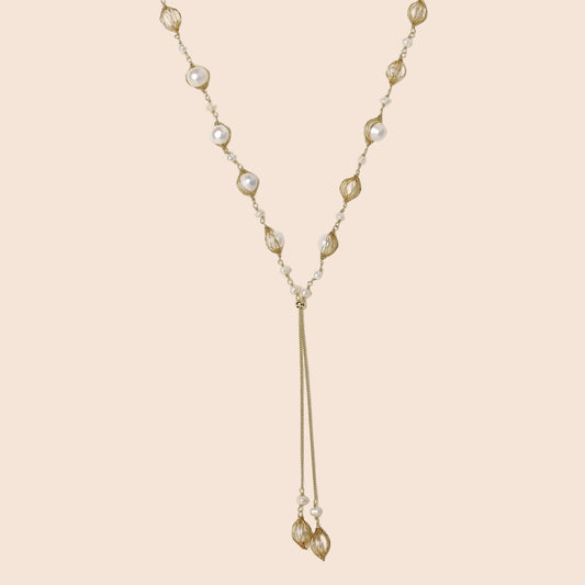 Adjustable gold lariat necklace with freshwater pearls nested in delicate cage settings and Y-shaped tassel drop