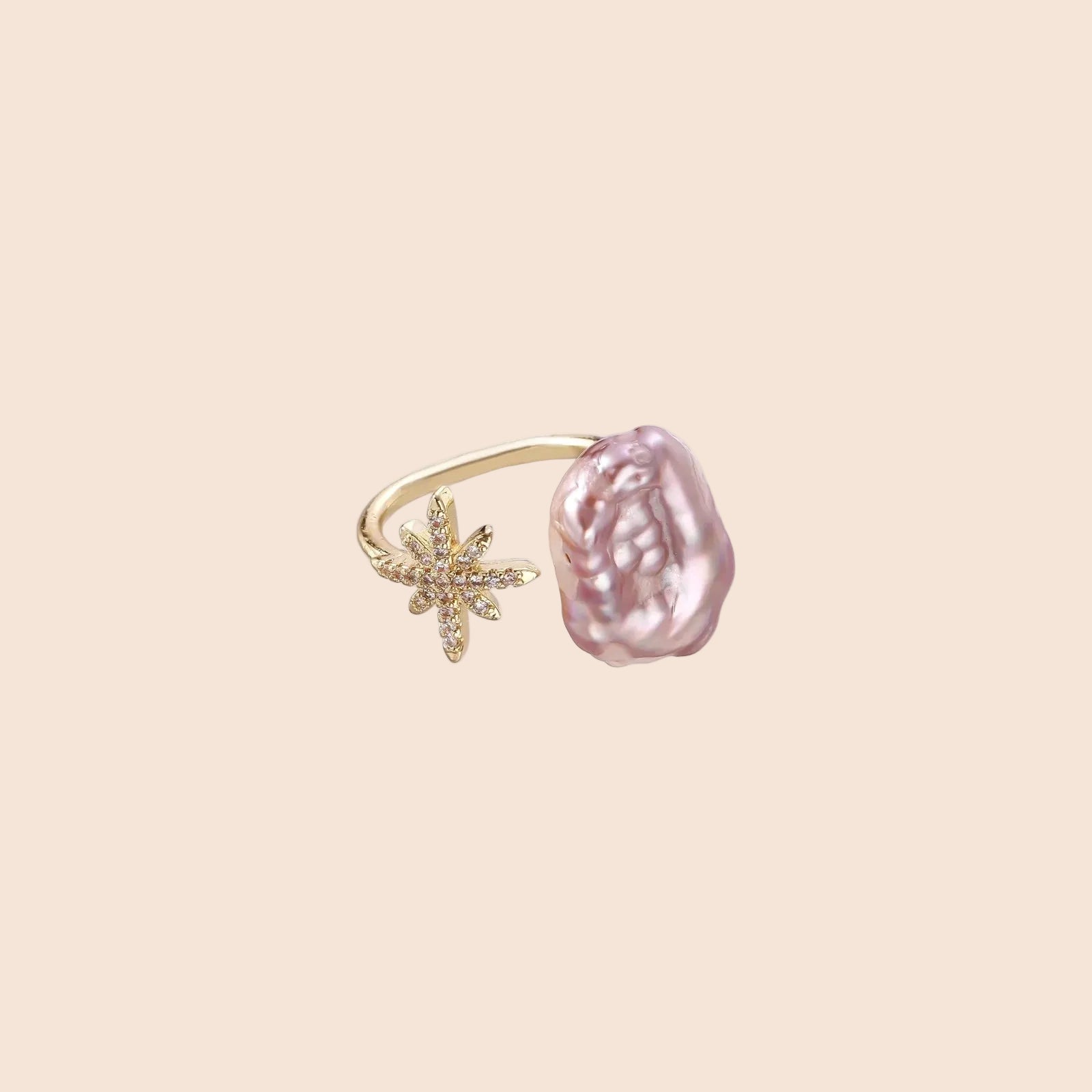 Adjustable gold ring with pink baroque freshwater pearl and crystal-studded star charm on white background
