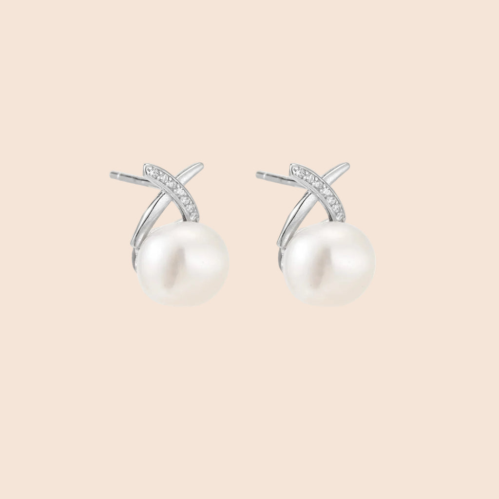 Rhodium-plated silver stud earrings with sparkling X design above lustrous round freshwater pearls on white background.