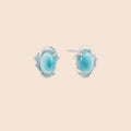 Oval larimar gemstone studs with ornate silver settings showing natural turquoise marbling on cream background