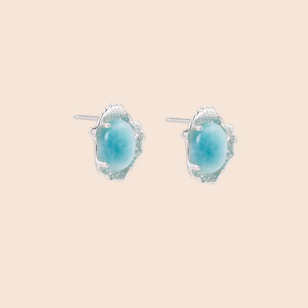 Oval larimar gemstone studs with ornate silver settings showing natural turquoise marbling on cream background