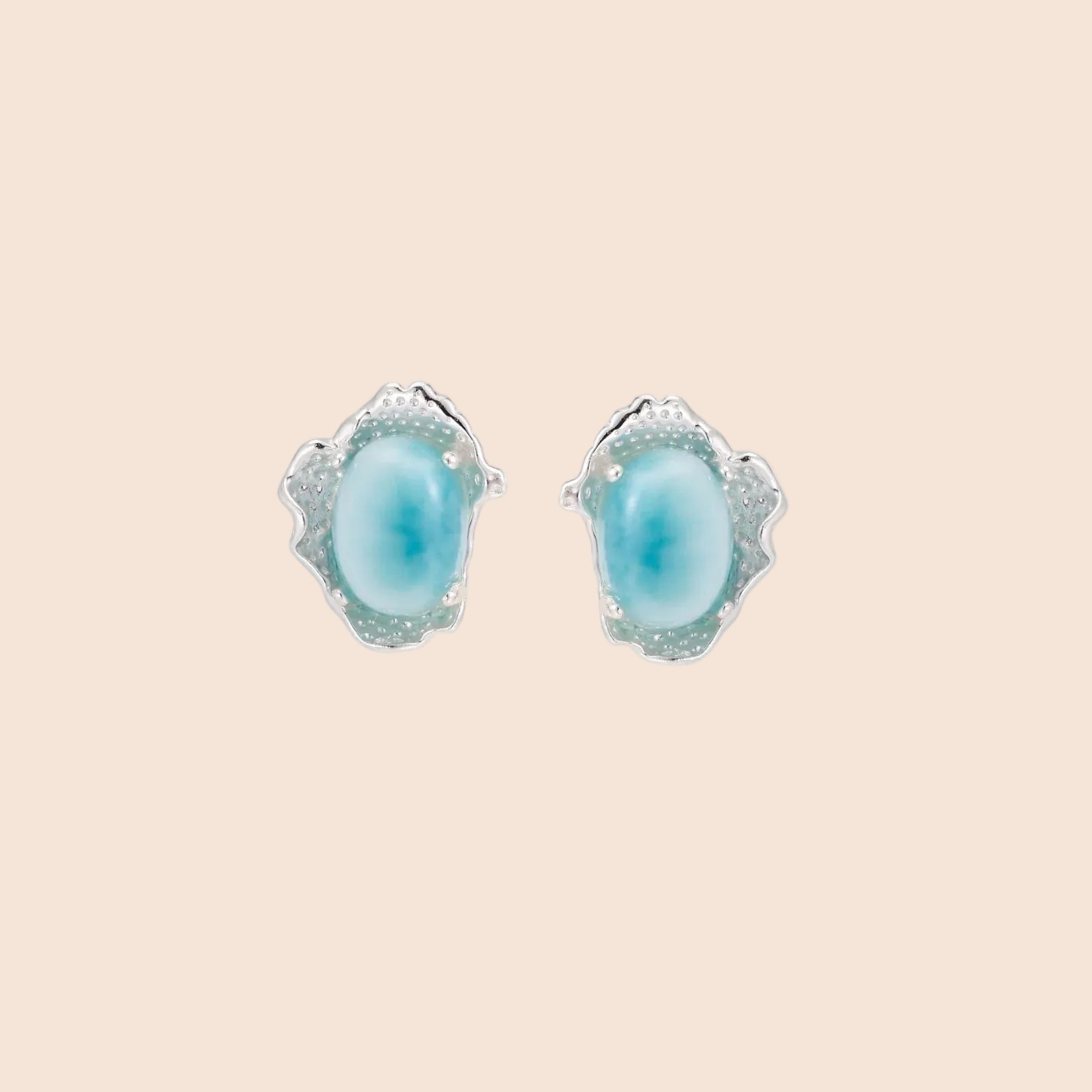 Oval larimar gemstone studs with ornate silver settings showing natural turquoise marbling on cream background
