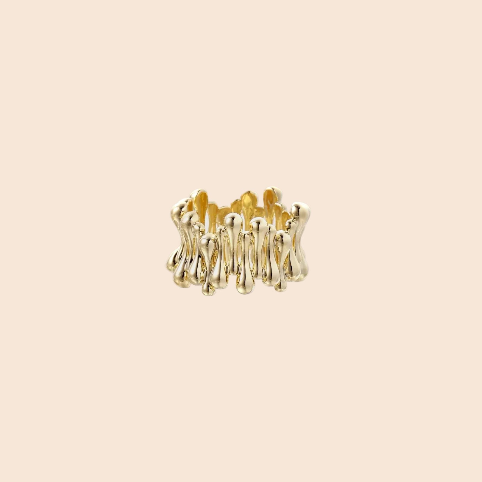 Gold-plated brass ring with sculptural petal-like elements in a wide band design on beige background