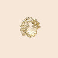 Gold-plated brass ring with sculptural petal-like elements in a wide band design on beige background