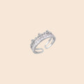 Silver-toned adjustable crown ring with channel-set square zirconia stones and delicate floral details on white background