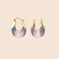 Gold hoop earrings with gradient blue-to-pink enamel in ribbed fan design on beige background