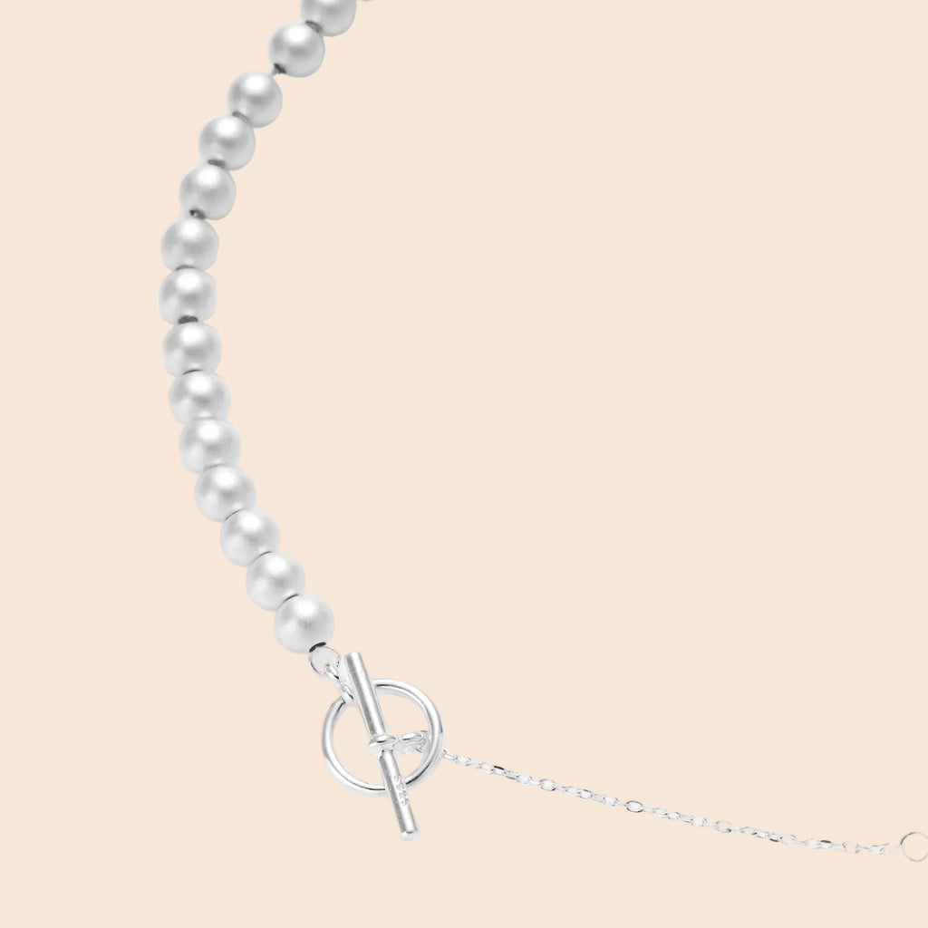 Long sterling silver beaded necklace with graduated sphere design, toggle clasp, and delicate chain extension on white background