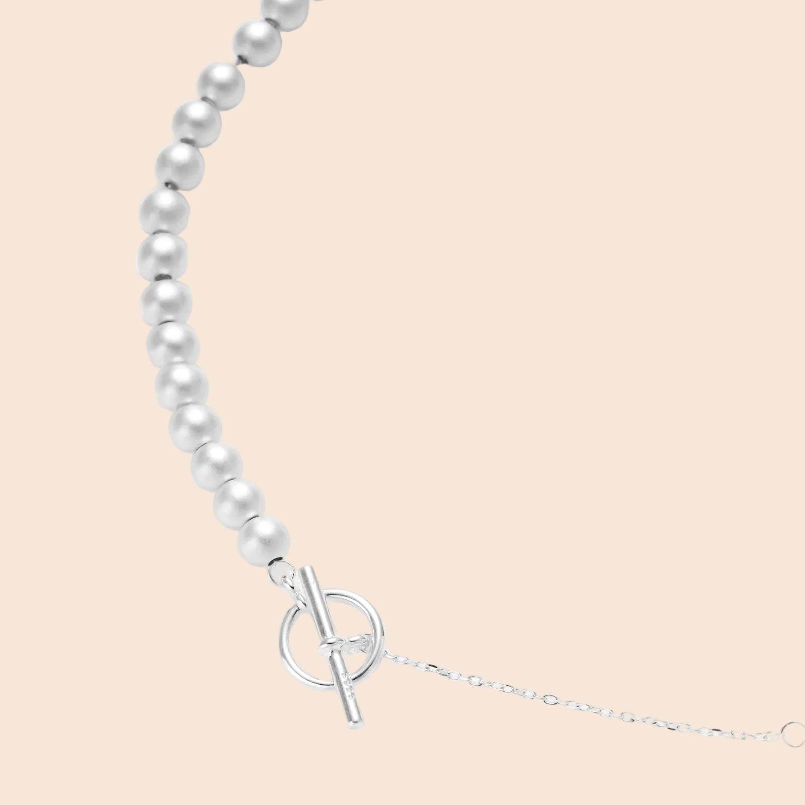 Long sterling silver beaded necklace with graduated sphere design, toggle clasp, and delicate chain extension on white background