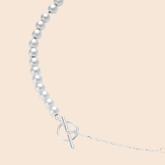 Long sterling silver beaded necklace with graduated sphere design, toggle clasp, and delicate chain extension on white background