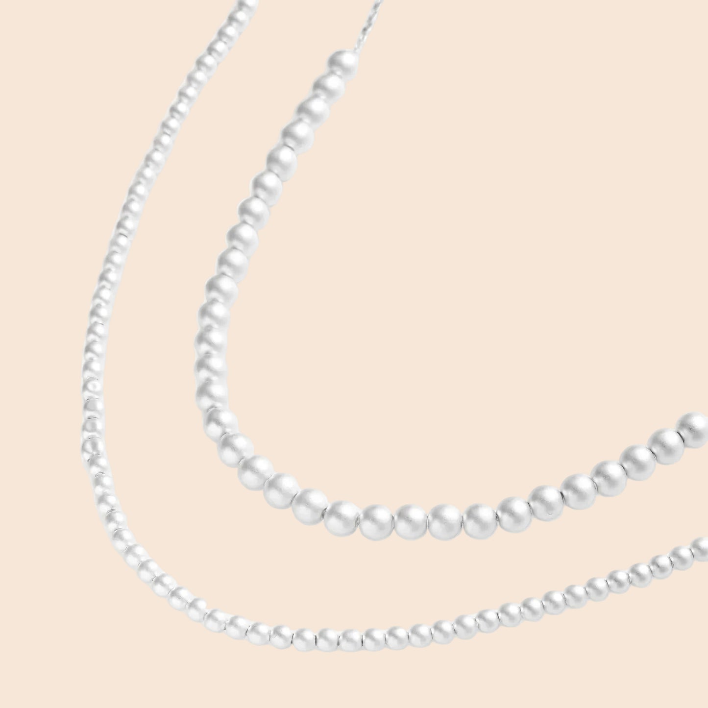 Long sterling silver beaded necklace with graduated sphere design, toggle clasp, and delicate chain extension on white background
