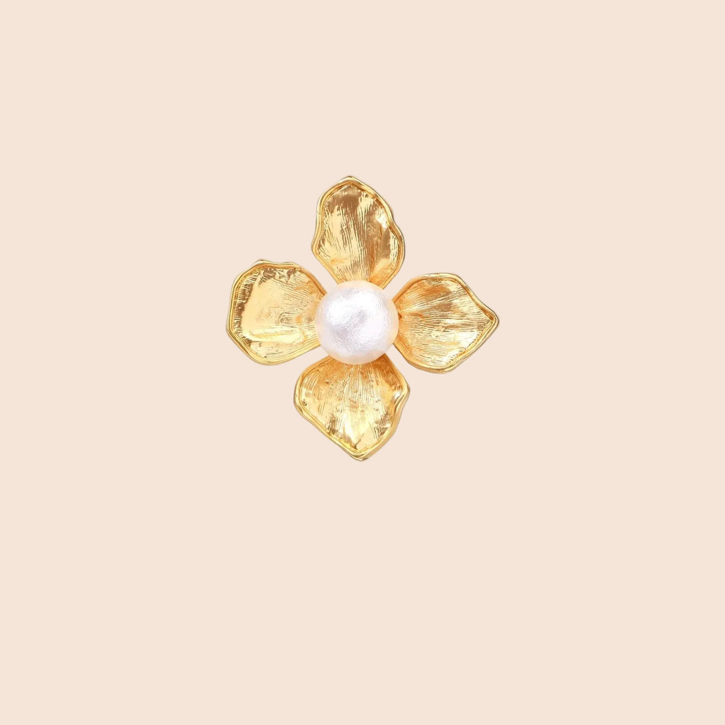 Gold-plated flower ring with textured petals and white cotton pearl center on cream background