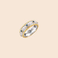 Two-tone ring with brushed silver center, gold beaded edges, and blue zirconia stones on white background.