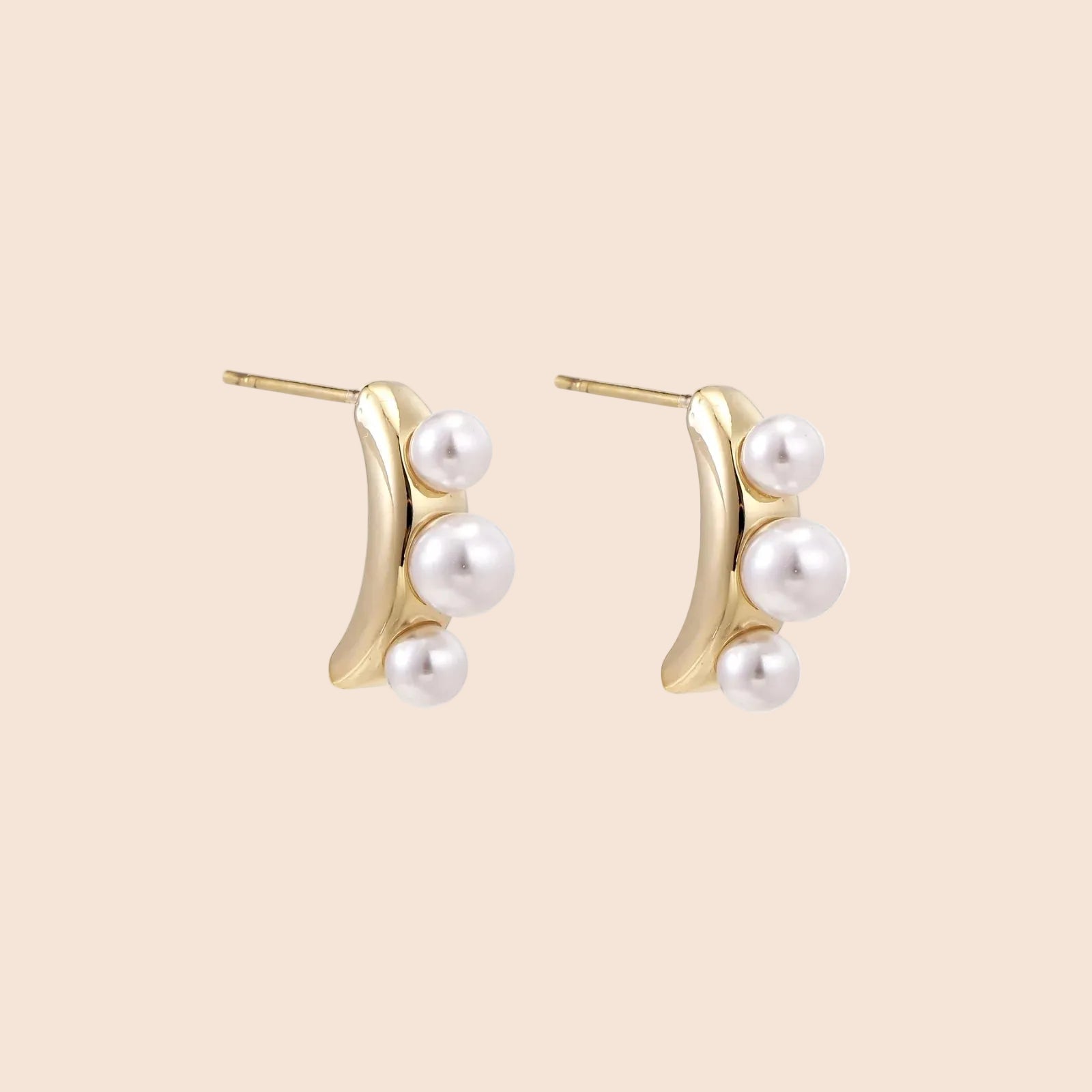 14K gold-plated curved stud earrings with three white freshwater pearls aligned vertically on cream background