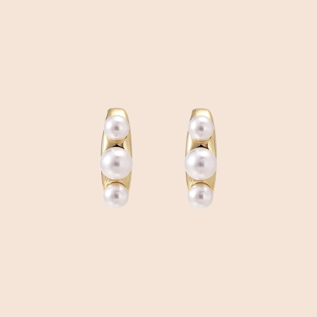14K gold-plated curved stud earrings with three white freshwater pearls aligned vertically on cream background