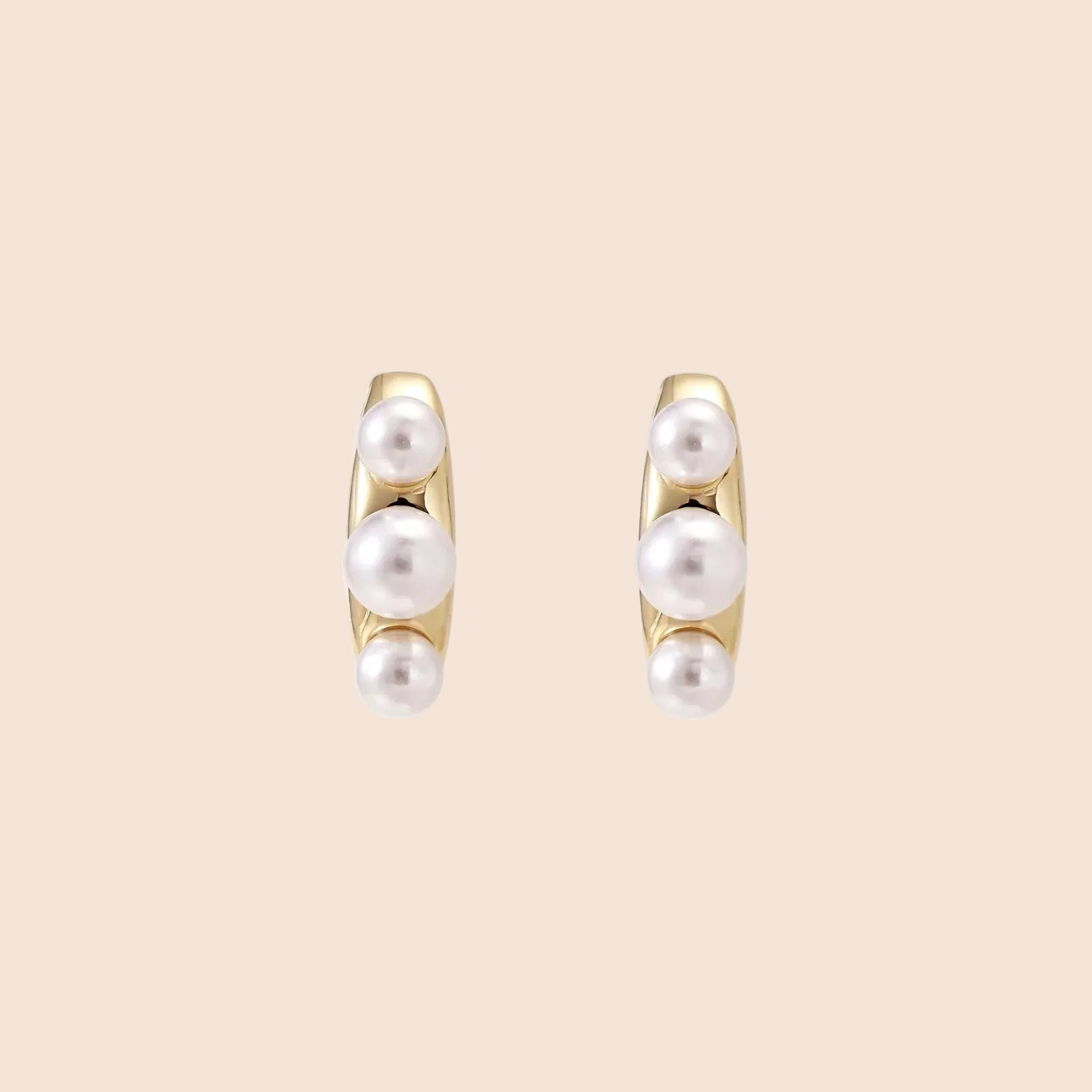 14K gold-plated curved stud earrings with three white freshwater pearls aligned vertically on cream background