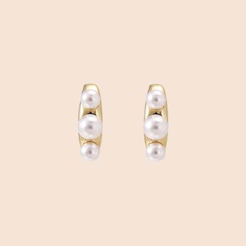 14K gold-plated curved stud earrings with three white freshwater pearls aligned vertically on cream background