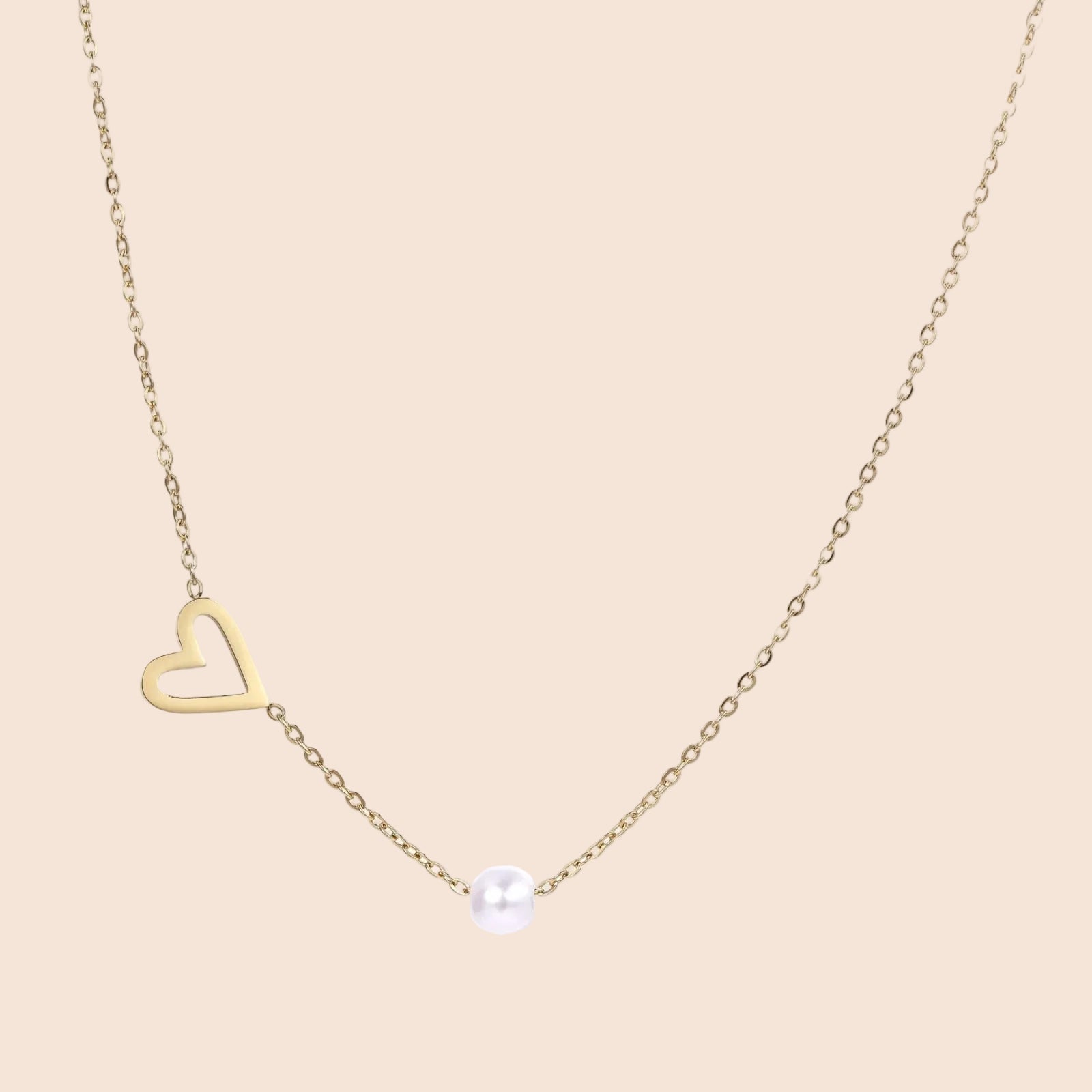 Delicate gold necklace with open heart charm and white pearl bead on fine chain against cream background