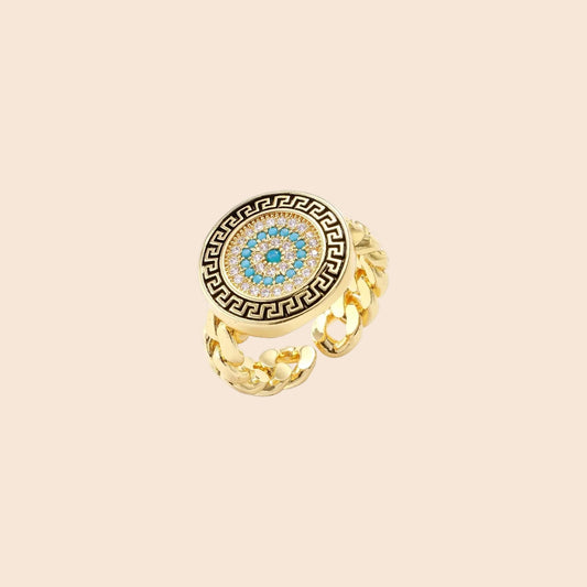 Gold chain ring with Greek key border and turquoise evil eye center on white background