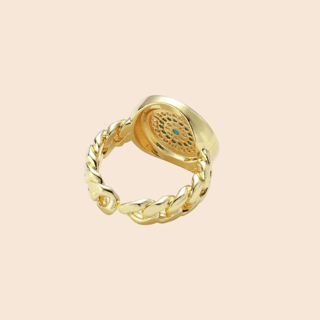Gold chain ring with Greek key border and turquoise evil eye center on white background