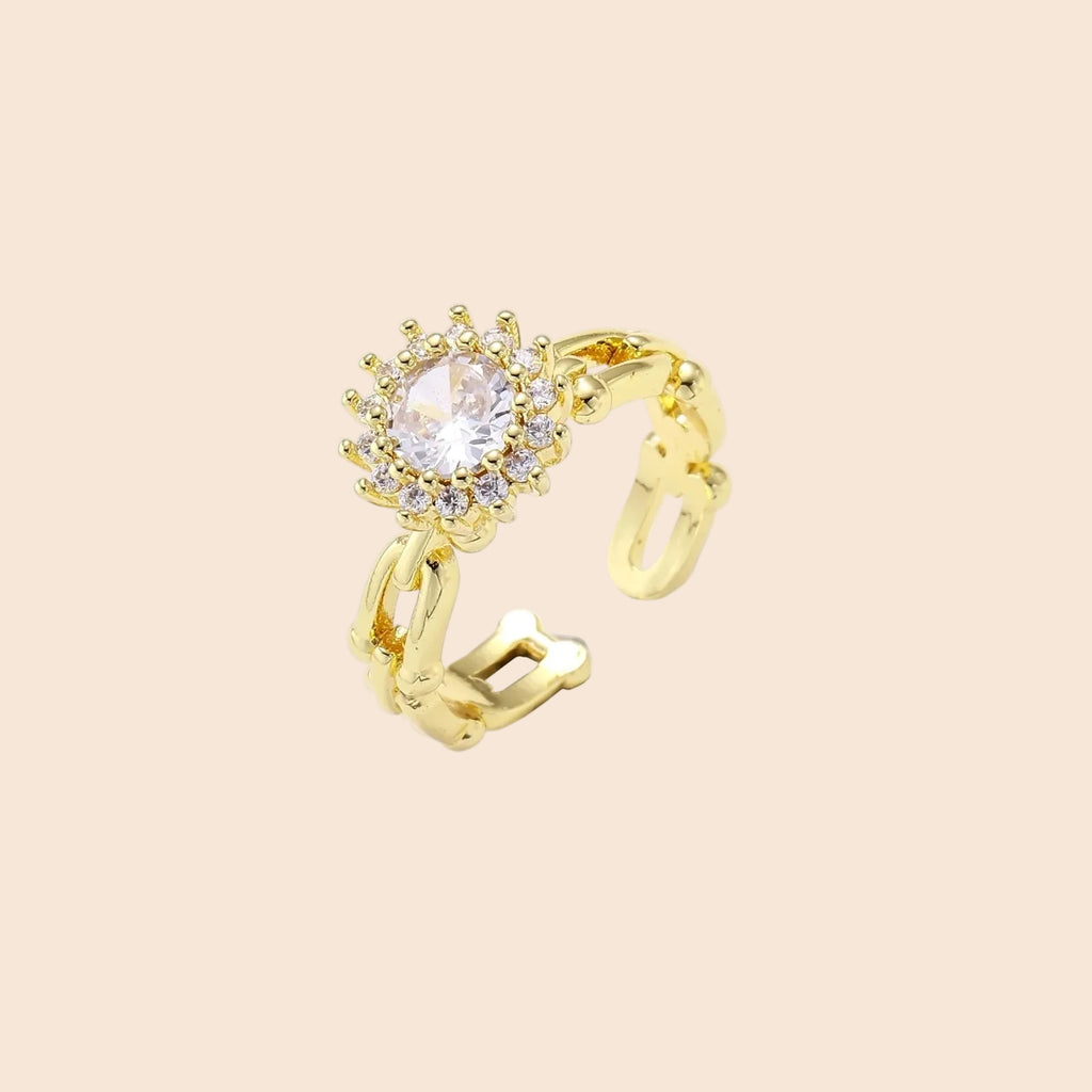 Two adjustable gold rings: chain-link band and halo-style ring with cubic zirconia stones on cream background