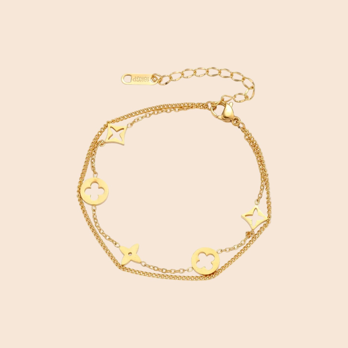 Double-layer gold-plated bracelet with quatrefoil and star charms on cream background, 18K gold finish.