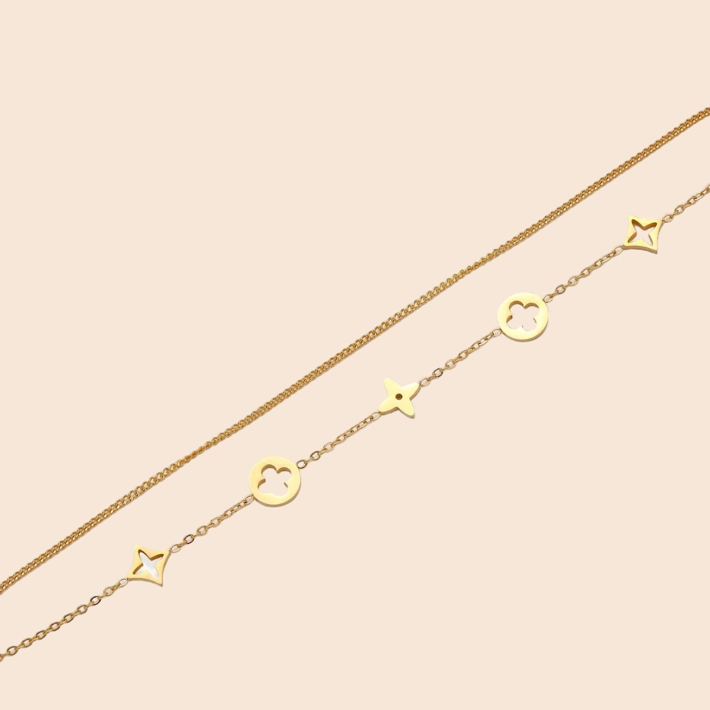 Double-layer gold-plated bracelet with quatrefoil and star charms on cream background, 18K gold finish.