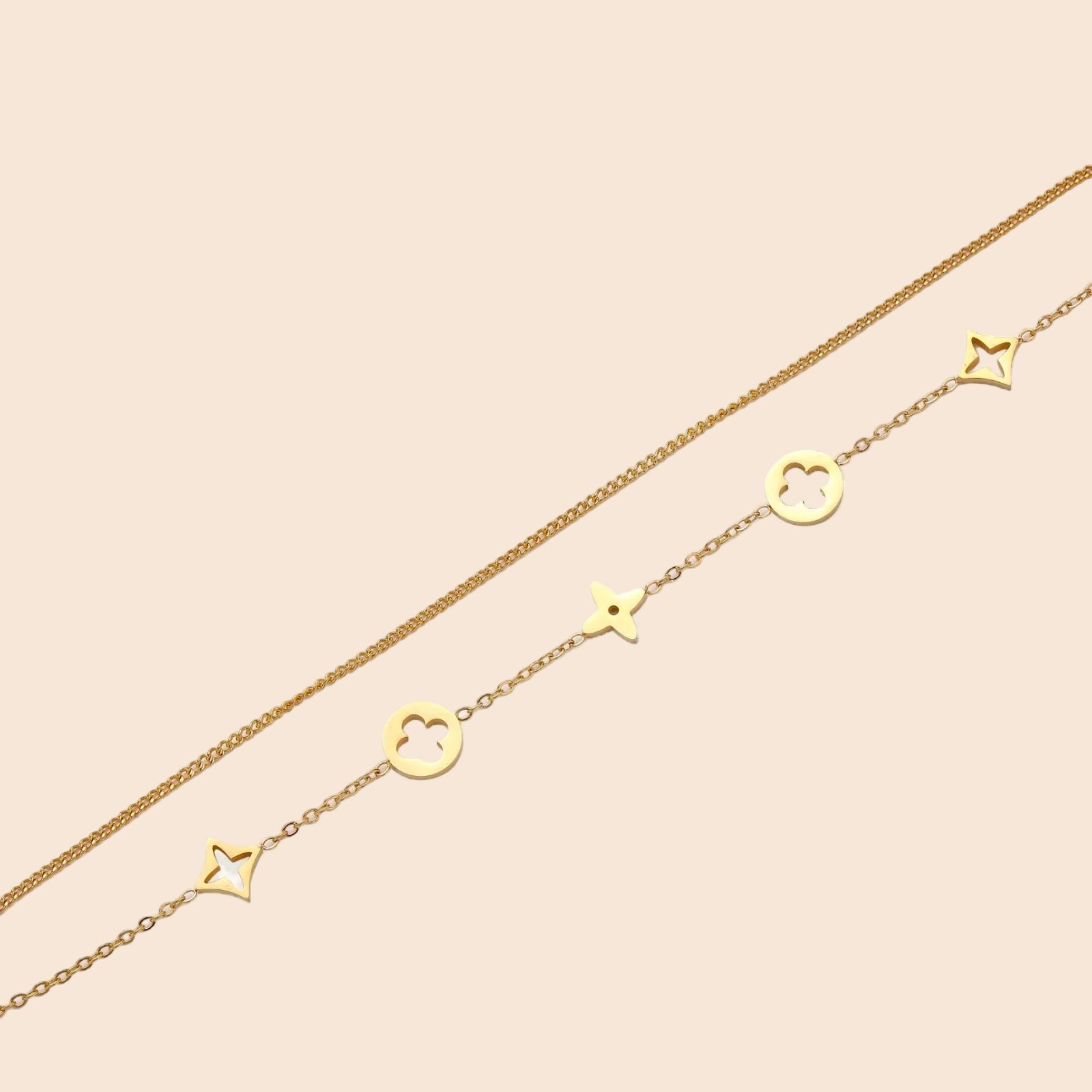 Double-layer gold-plated bracelet with quatrefoil and star charms on cream background, 18K gold finish.