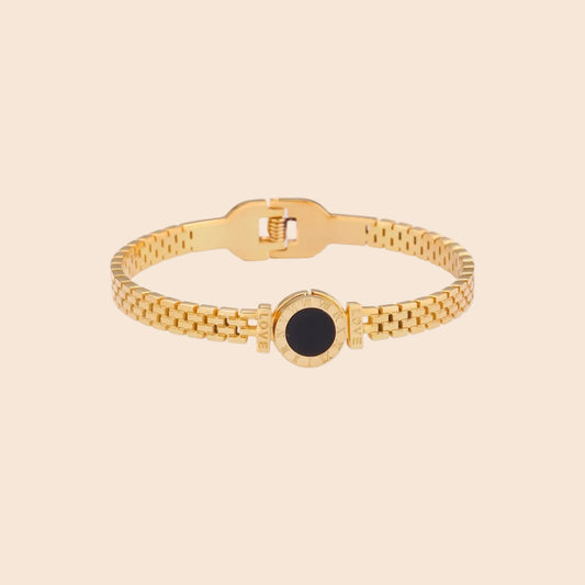 Gold mesh bracelet with circular black mother of pearl medallion featuring Roman numeral engravings and hinged clasp
