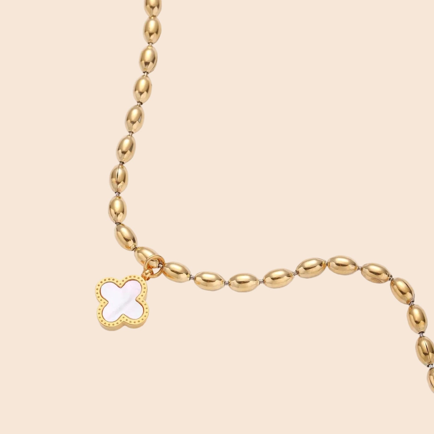 18K gold-plated oval bead chain bracelet with quatrefoil clover charm featuring mother of pearl inlay on cream background