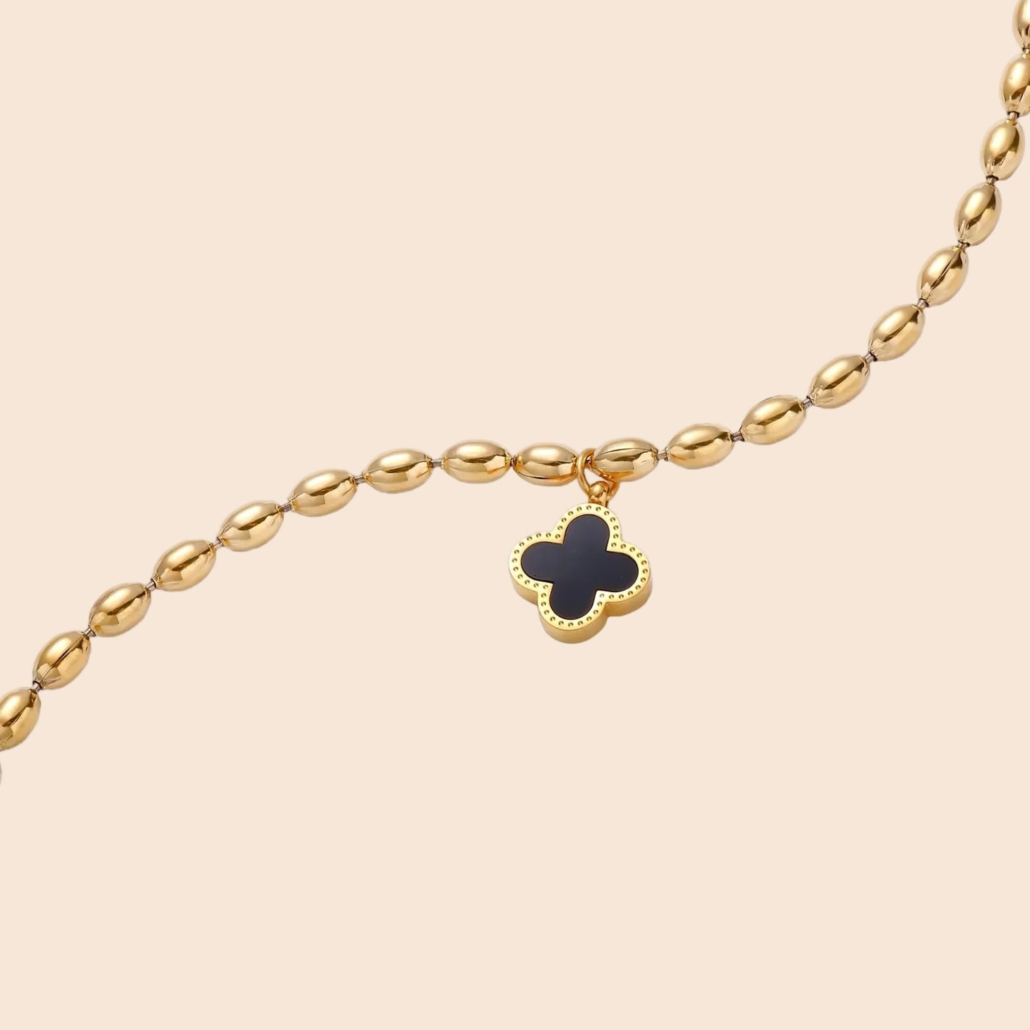 18K gold-plated oval bead chain bracelet with quatrefoil clover charm featuring mother of pearl inlay on cream background