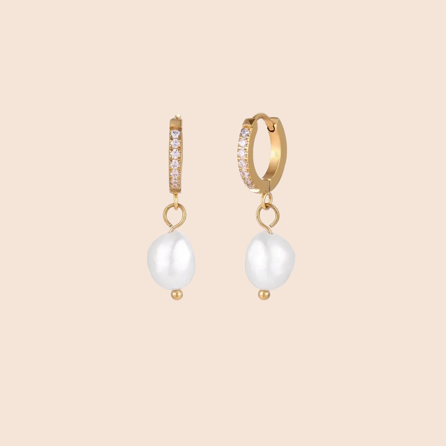 Gold huggie hoop earrings with pavé crystals and white freshwater pearl drops on cream background