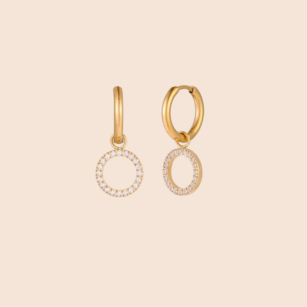 Gold-plated huggie hoop earrings with CZ-studded open circle charms on beige background