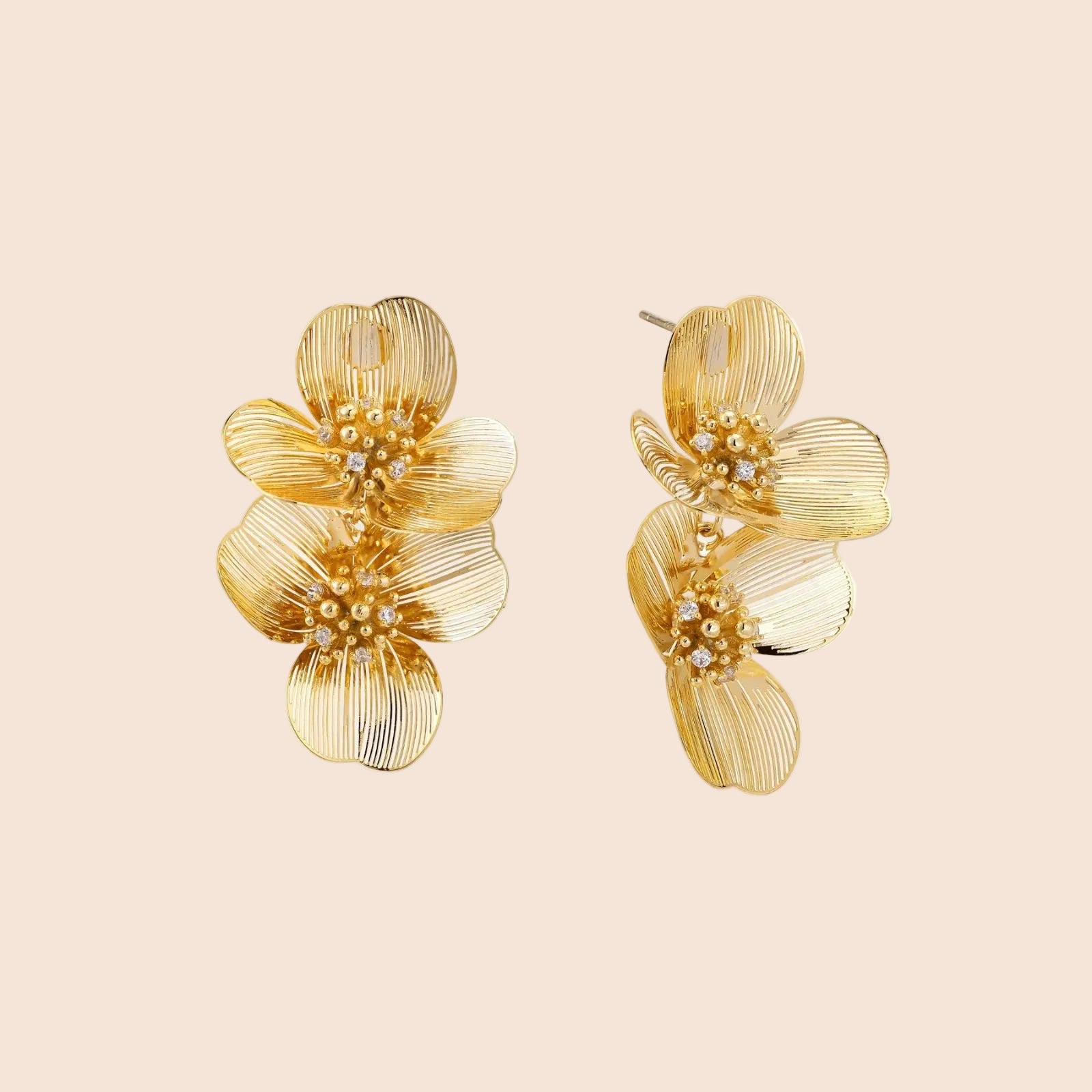 Pair of gold-plated double flower earrings with textured petals and crystal centers on cream background.