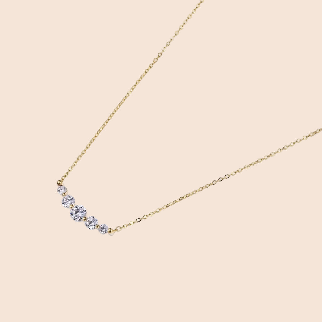 Delicate 14K gold-plated necklace with five graduated zirconia stones arranged in a curved arc on fine chain