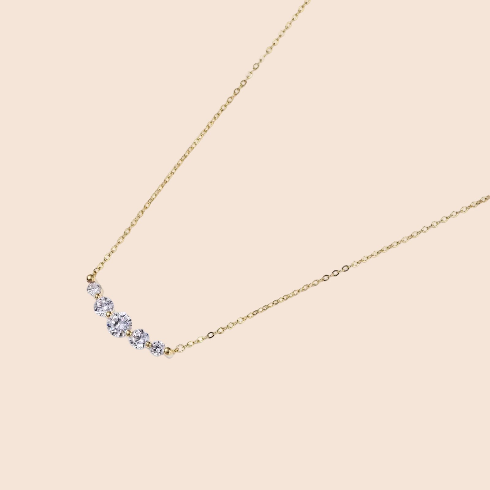 Delicate 14K gold-plated necklace with five graduated zirconia stones arranged in a curved arc on fine chain