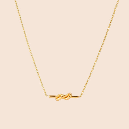 Dainty 18K gold plated necklace with infinity knot pendant on delicate chain against white background