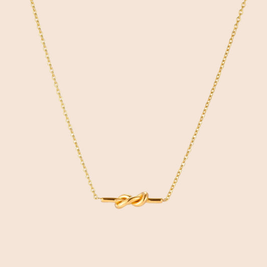 Dainty 18K gold plated necklace with infinity knot pendant on delicate chain against white background