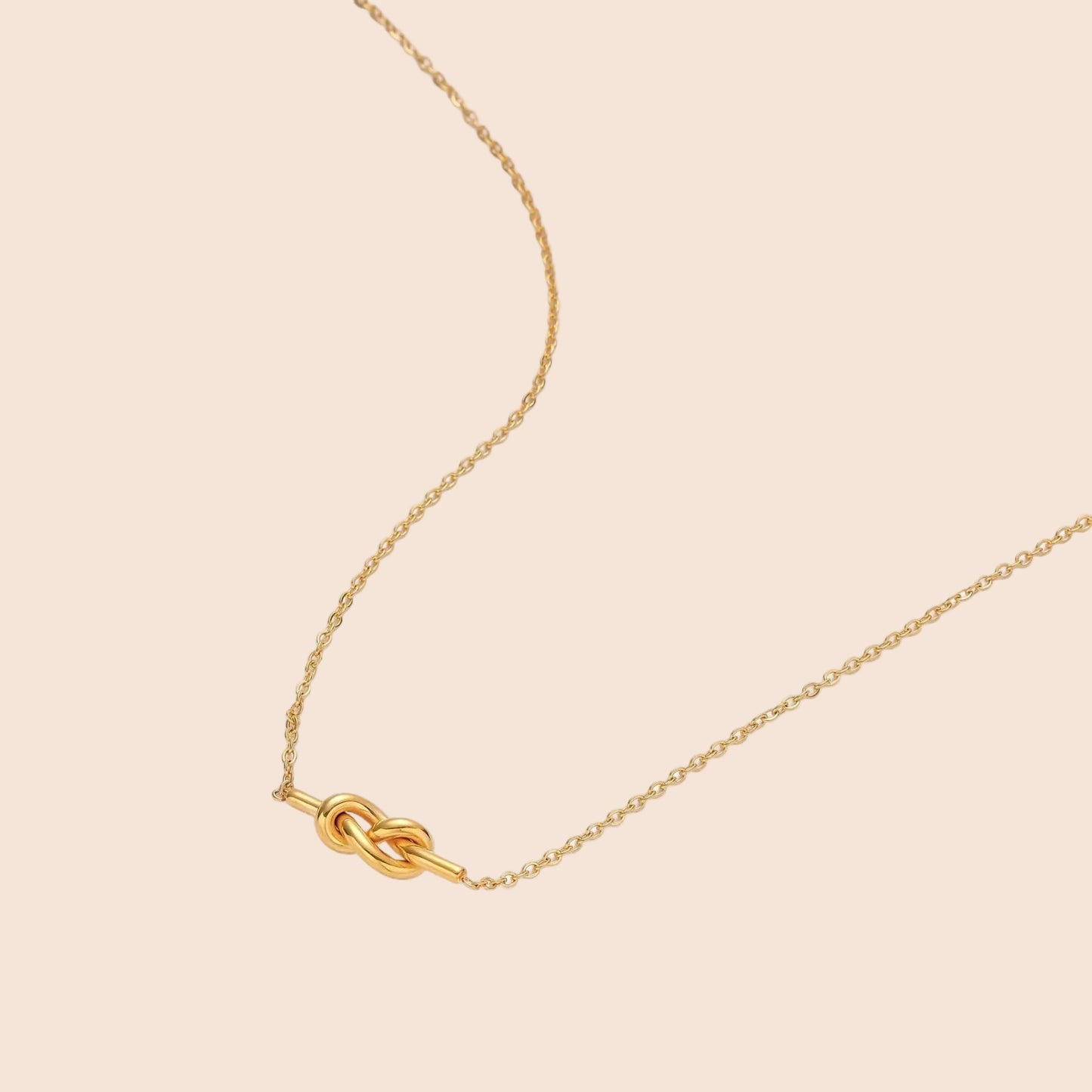 Dainty 18K gold plated necklace with infinity knot pendant on delicate chain against white background