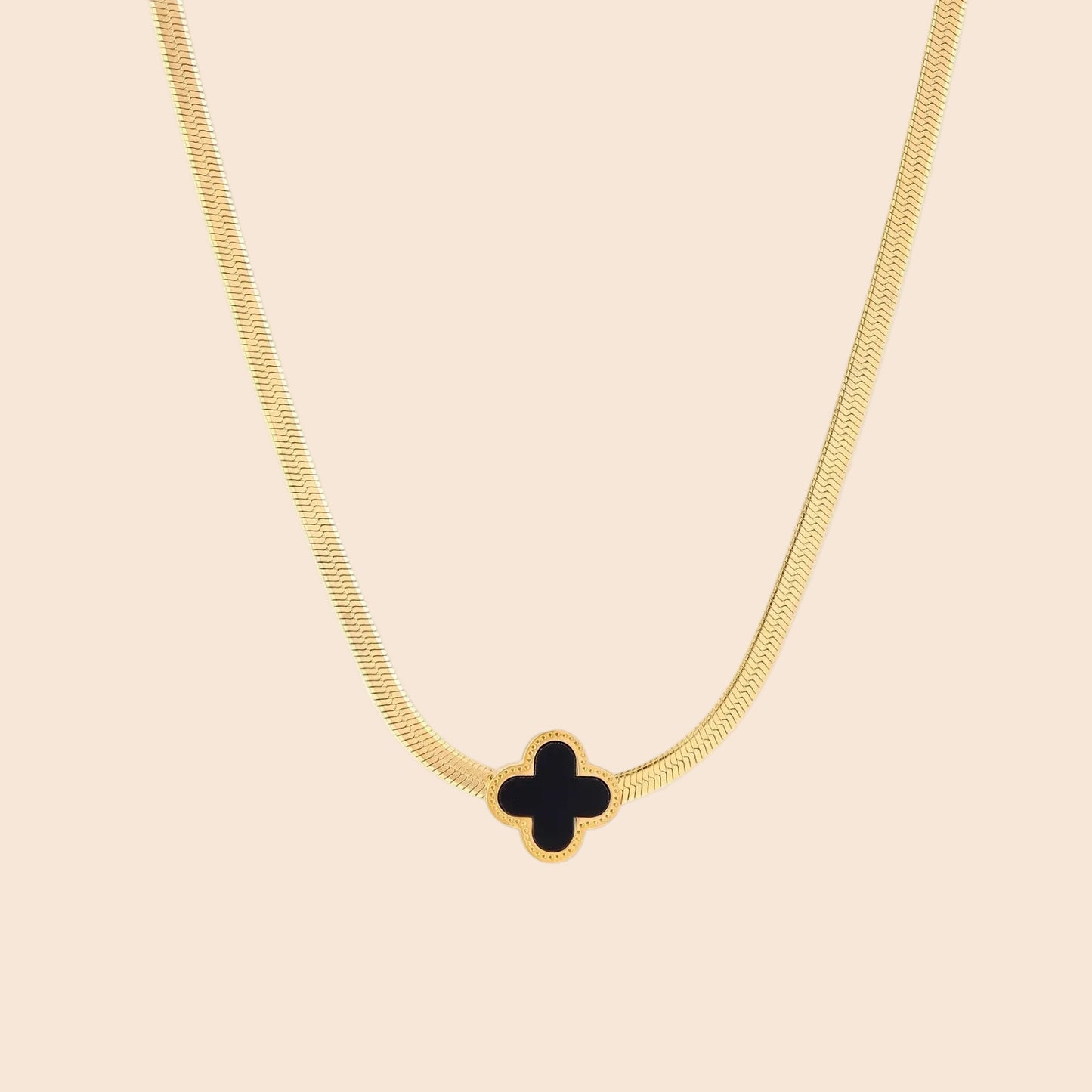 Dainty 18K gold-plated herringbone chain necklace with black enamel quatrefoil clover pendant on white background
