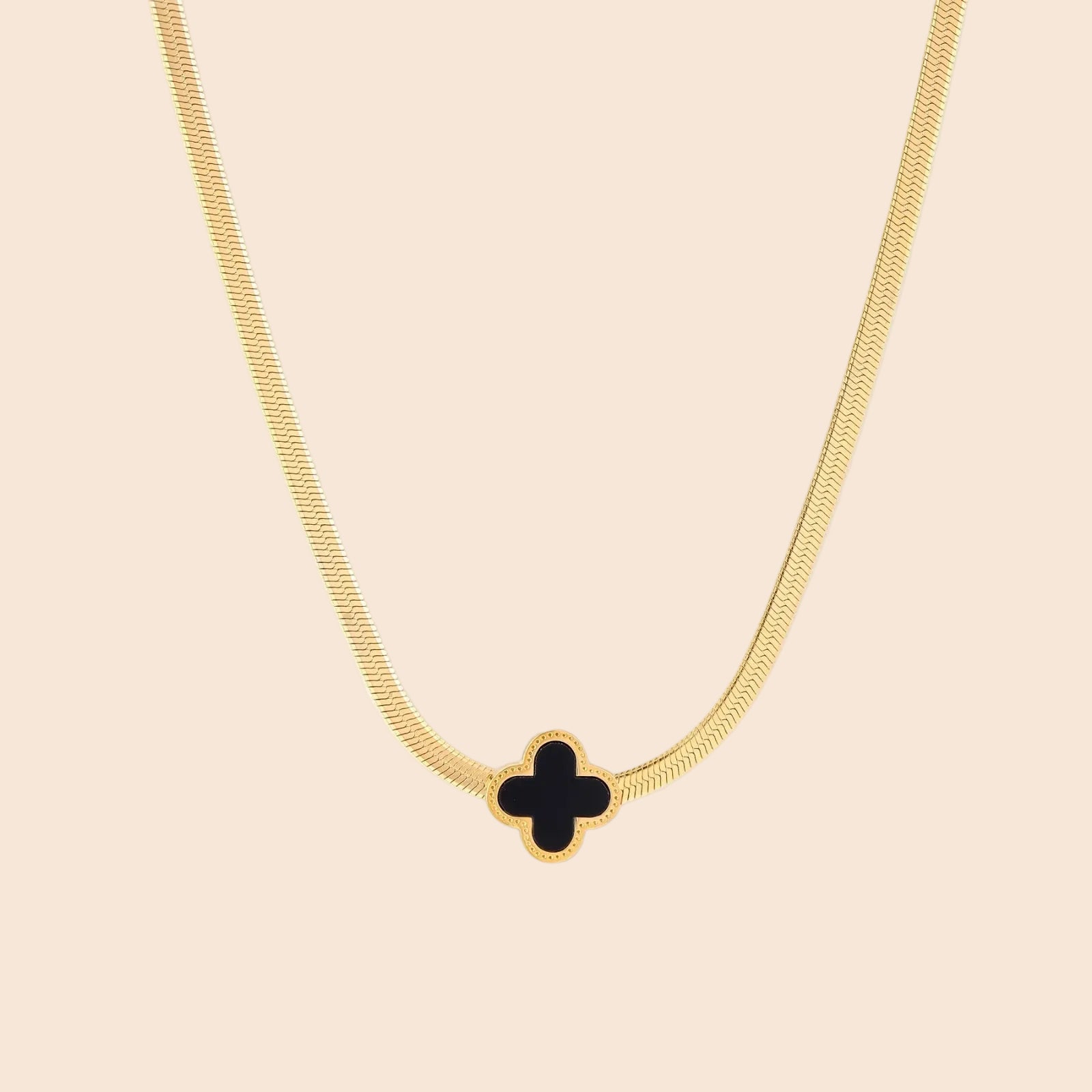 Dainty 18K gold-plated herringbone chain necklace with black enamel quatrefoil clover pendant on white background