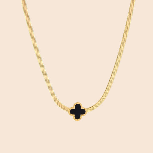 Dainty 18K gold-plated herringbone chain necklace with black enamel quatrefoil clover pendant on white background