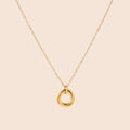 Delicate gold-plated necklace with three interlocking circle rings forming a minimalist knot pendant on cream background